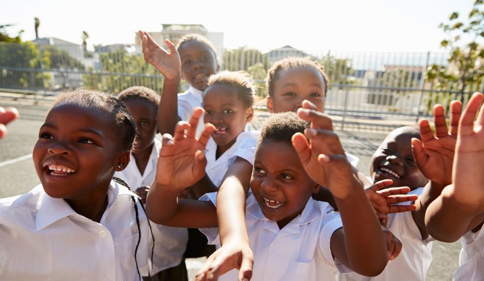 elementary-school-kids-in-playground-waving-to-P34BUTG.jpg